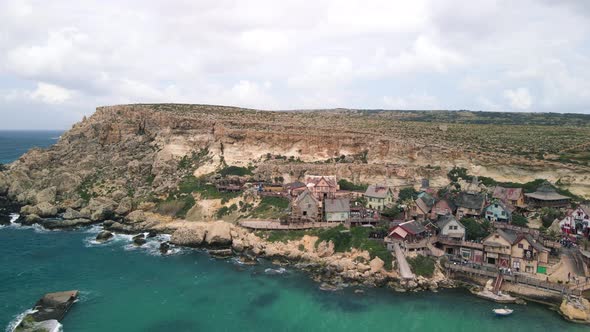 Aerial shot of Popeye village of Malta settle just near the sea in the rocky cliff. View of the famo
