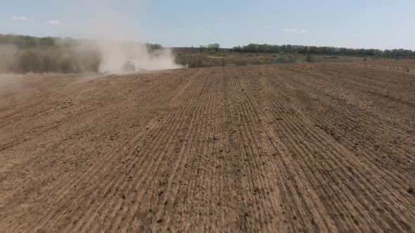 Tractor Plowing a Field with a Lot of Dust