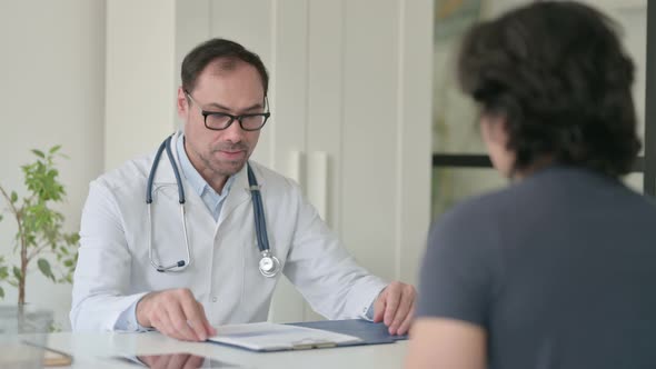 Middle Aged Doctor Talking to Patient in Office