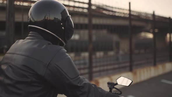 Young Attractive Man Motorcyclist with His Helmet and Custom Motorcycle on Street