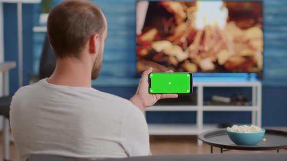 Closeup of Man Holding Smartphone with Green Screen Watching Online Video Content