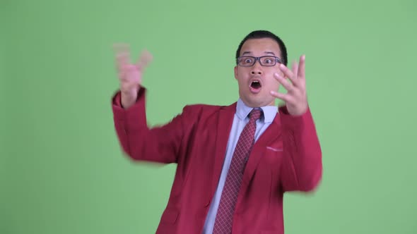 Happy Asian Businessman with Eyeglasses Pointing Finger and Looking Surprised