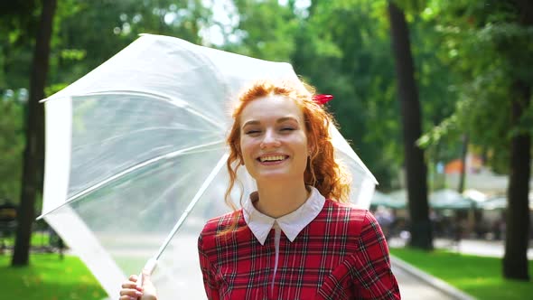 Happy female posing with umbrella in sunny park