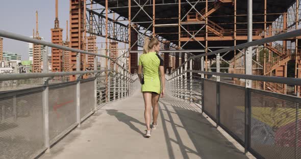 Young Blond Woman in Fitness Wear Warming Up on Walkway for Running Training