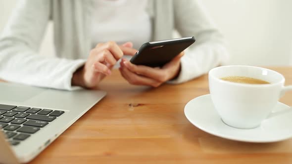 Woman sending text message on mobile phone and drink of coffee