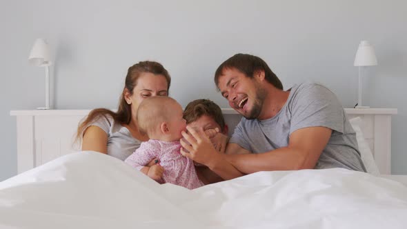 Happy Family with Cute Little Kids Son Daughter Tickling Having Fun Relax on Bad Together Young