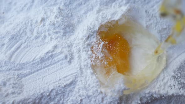 Slow motion of egg falls on a pile of flour