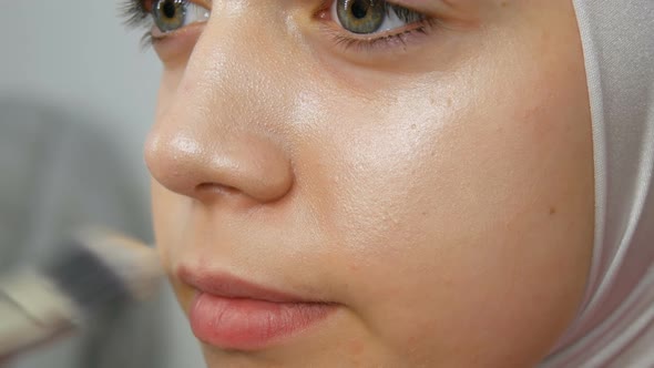 A Professional Makeup Artist Applies a Concealer to the Girl Model with Special Brush