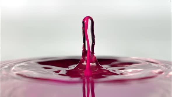 Water splashing as pink droplet falls into surface