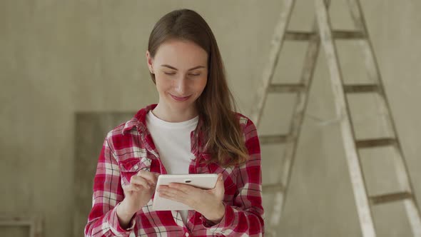 Young Woman Stand in New Apartment Using Tablet Choosing New Design of House