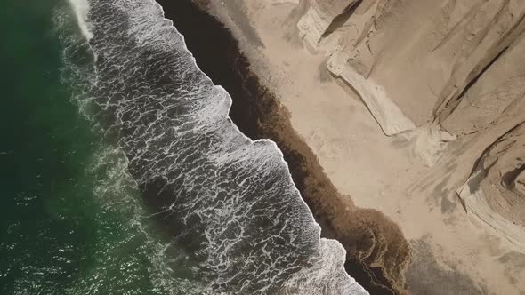 Waves on the black sand beach of Santorini in Greece - aerial view