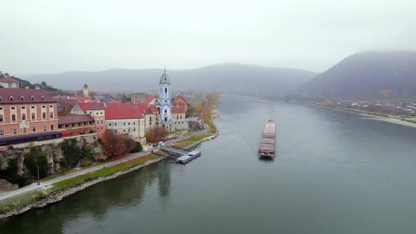 Cargo Pusher Boat on a River Transporting Cargo and Goods Past a Town