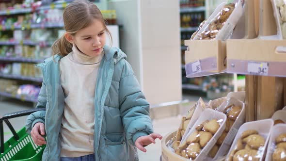 a Little Girl Chooses Sweet Pastries on the Counter in the Store