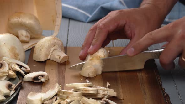 Men Hands Cutting Champignons with a Knife on Kitchen Table