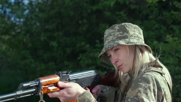 Closeup Woman in Uniform in Zone of Armed Conflict Aims with an Assault Rifle