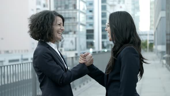 Two Smiling Women Meeting on Street and Shaking Hands