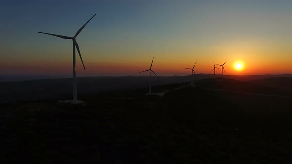 Sun setting behind elegant windmills on a hill