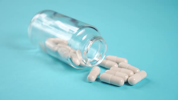 Medical capsules in a glass pharmaceutical bottle on a blue bright table 