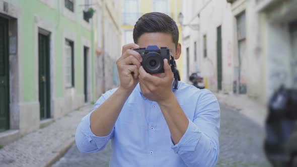 Focused Young Photographer Taking Pictures on Street