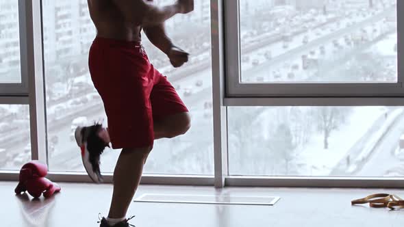 Muscular Shirtless Man Jumps Over Rope in Studio with Panoramic Windows  Boxer Gloves on the Floor