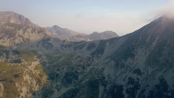 Wide aerial drone slowly dropping facing a mountain range.