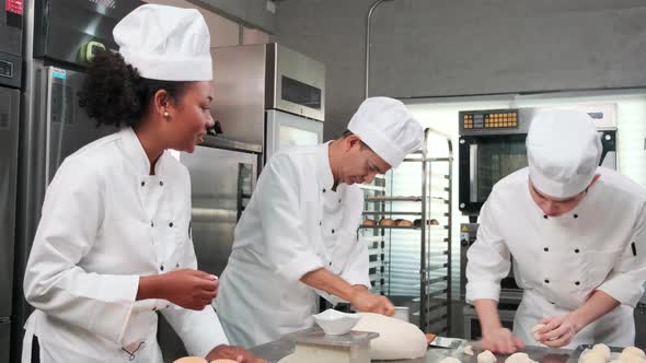 Chefs team in uniforms prepare to bake bread and pastry in stainless kitchen.