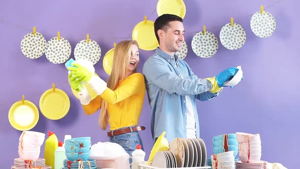 Positive Awesome Young Man and Woman Looking at Each Other While Wiping Plates