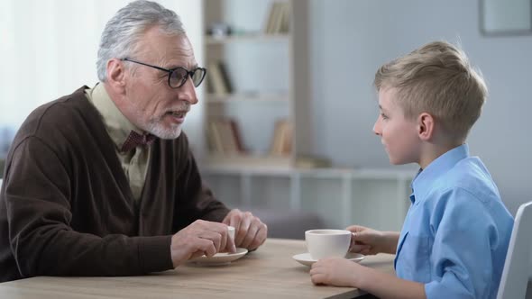 Grandfather Telling Grandson Funny Stories, Family Leisure Over Cup of Cocoa