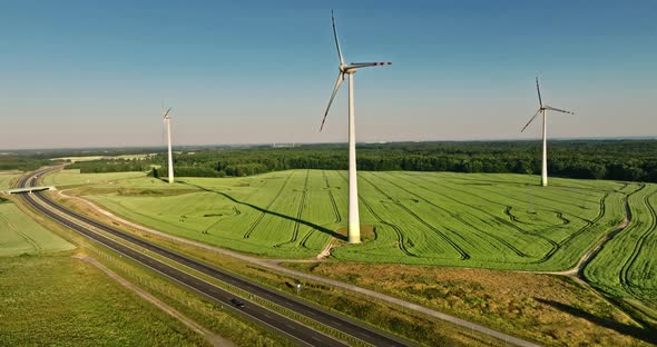 Wind turbines and green field near highway, aerial view