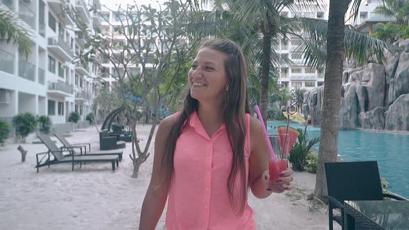 Beautiful Girl Walks Around Hotel Near Tall Green Palms