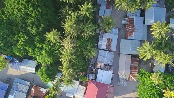 Aerial flight over local village huts and forest on island in Malaysia, birds eye perspective moving