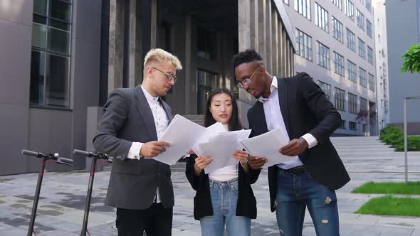 Creative International Team Browsing Financial Reports and Throwing them Up After Ending Joint Work