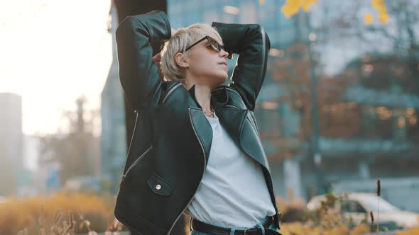 Young Woman with Bright Hair and Sunglasses Posing in Park with Hands Over the Head. People and