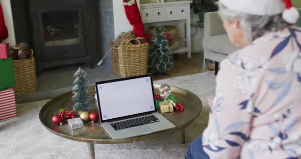 Caucasian senior couple in santa hats on video call on laptop with copy space at christmas time