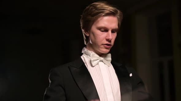 Close-up and slow motion of a young conductor who directs orchestra