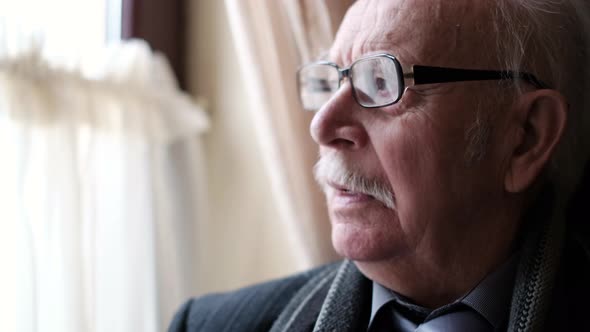 An Elderly Grayhaired Man is Sitting in a Room Alone He is Looking Out the Window