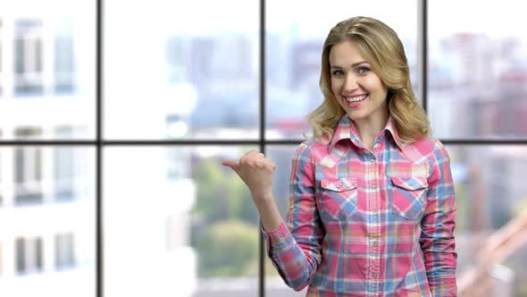 Cheerful Woman Pointing Thumb Aside Behind Her Back