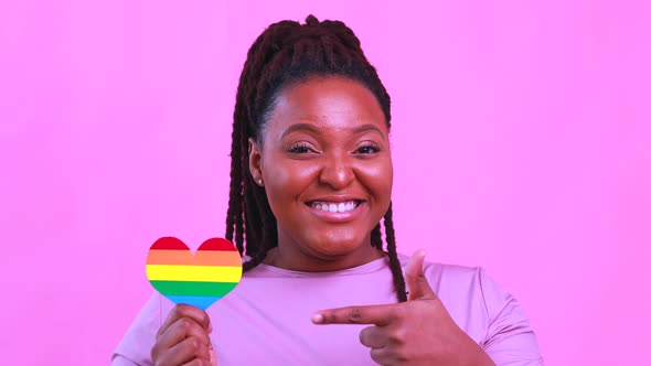 Afro American Woman Holding a Heart Shape in Pink Studio Background