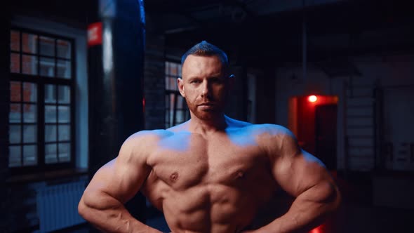 Strong Man Standing in the Gym and Looking in the Camera