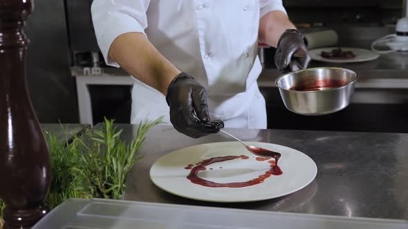 Closeup of the Chef Serving Dishes in the Kitchen He Pours Sauce on a Plate