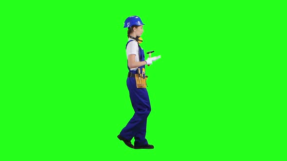 Worker Girl Comes with a Hammer in Her Hands and in a Helmet. Green Screen. Side View