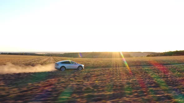 Aerial Shot of Electrical Car Moving on Offroad Route Leaving Dust Trail Behind