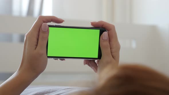 Female in bedroom resting with greenscreen device 4K 2160p 30fps UltraHD footage - Woman in hands ho