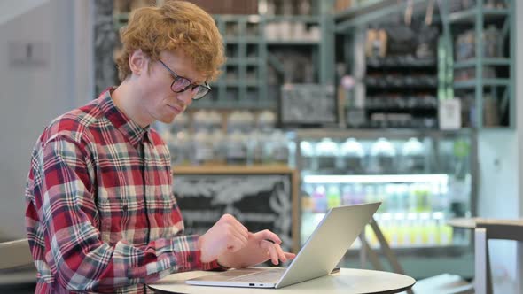 Young Redhead Man with Laptop in Cafe Having Wrist Pain