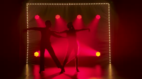 A Romantic Couple of Ballroom Dancers Are Dancing in the Studio Against the Background of Red