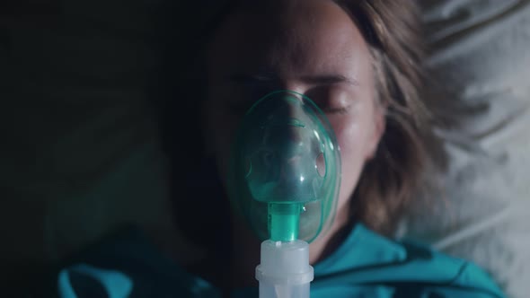 A Female Patient in Medical Mask is Breathing Oxygen Support in a Hospital Next to Heart Rate