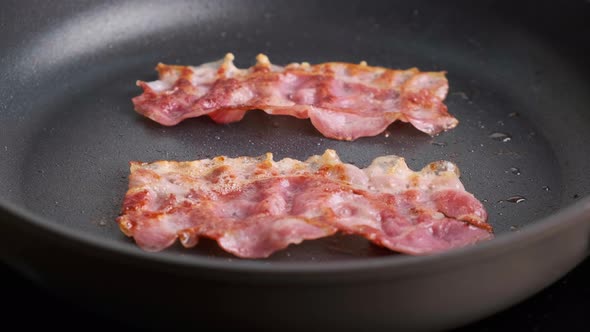 Fried Strips of Bacon on Black Frying Pan