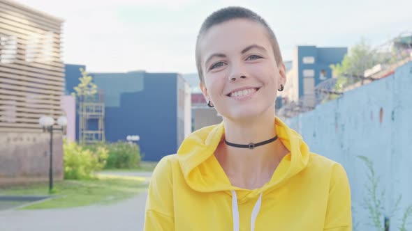 Close Up of Laughing and Smiling Young Attractive Woman with Shaved Hair in Street Urban Background