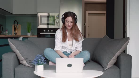 Young Woman Wears Headset Conference Calling on Laptop Talks with Online Teacher Studying Working