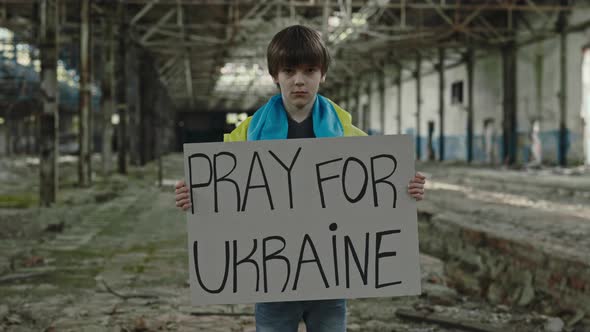 Portrait of the Boy with Ukrainian Flag Holding Pray for Ukraine Banner alt